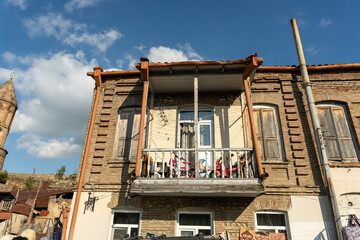 Wall Mural - A building with a balcony and a window. The balcony is empty. The building is old and has a lot of character