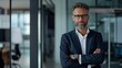 © Ali - portrait of a successful confident businessman standing in modern office with crossed hands
