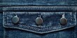 © Studio - Closeup of blue denim jeans pocket with three shiny metal buttons centered at the top showcasing intricate fabric texture against a dark background