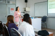 © EduLife Photos - A lecturer stands at the front of the classroom, engaging students with a presentation projected on the screen. The students sit at desks, focused on the lecture.