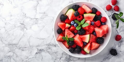 Wall Mural - Vibrant watermelon and berry salad in a white bowl on a light marble table with fresh mint leaves garnishing the dish and ample negative space for text