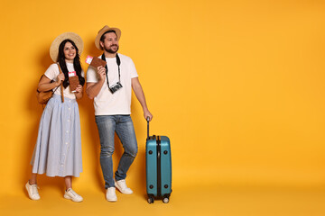 Sticker - Tourism. Happy couple in hats with suitcase, passports and tickets on yellow background, space for text