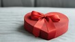 © Arfa_Media - Red heart-shaped gift box with a ribbon bow is lying on a soft fabric surface
