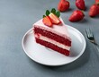 piece of red velvet cake with pink cream decorated with strawberries on a white plate on a grey background with strawberries copy space concept dessert sweet food classic american dessert