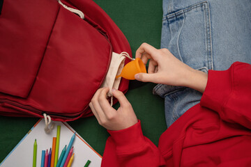 Wall Mural - An unrecognizable young girl takes out a menstrual cup from her backpack