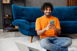 © ViDi Studio - Young IT man wear casual clothes sit on blue sofa couch work hold mobile cell phone use laptop pc computer stay home hotel flat rest relax spend free spare time in living room indoor. Lounge concept.