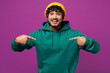 © ViDi Studio - Young shocked surprised overjoyed happy Indian man he wear green hoody yellow hat casual clothes point index finger on himself isolated on plain purple background studio portrait. Lifestyle concept.