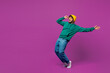 © ViDi Studio - Full body side view young shocked fun Indian man in green hoody yellow hat sunglasses casual clothes lean back stand on toes look aside on area isolated on plain purple background. Lifestyle concept