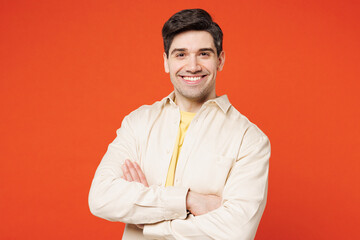 Poster - Young smiling happy cheerful confident man he wears white shirt yellow t-shirt casual clothes hold hands crossed folded look camera isolated on plain red orange background studio. Lifestyle concept.