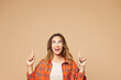 © ViDi Studio - Young smiling happy woman she wear orange shirt casual clothes point index finger overhead indicate on area mockup isolated on plain pastel light beige background studio portrait. Lifestyle concept.