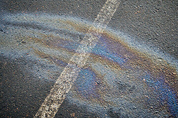 Wall Mural - Slick surface in a parking space, revealing an oil spill from an automobile, delineated by a white marking.