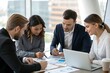 © ARTSPRIO - Group of people are sitting around a table with a laptop and papers