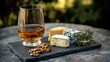 © designer - Snifter glass of aromatic cognac served with an assortment of fine cheeses and walnuts on a slate platter outdoors