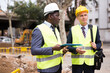 © JackF - Two men workers working at the laying paving slabs facility discuss the project, holding important work documents