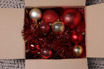 Wall Mural - Shiny tinsels and baubles in cardboard box on carpet, top view