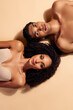 © Beauty Hero - Stunning couple lying on beige background, embracing sensual connection and natural beauty, top view photo