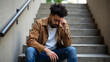 © MarGa - Young African American man sitting on stairs, hand on head, looking distressed. Concept for emotional awareness and support during Marijuana Awareness Month
