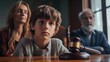 © masyastadnikova - Sad boy sitting at a table in the background of his parents.