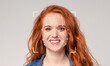 © Prostock-studio - A woman with vibrant red hair is smiling warmly. Her facial features are being analyzed using advanced recognition technology marked with geometric shapes, emphasizing identification.