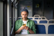 © DimaBerlin - Man absorbed in music and podcasts through earbuds, traveling to work on train with smartphone. Audio engagement and getting away, commuter life, solo travel and tourism, modern technology