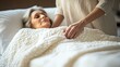 © zen - A spouse adjusting the blankets around their ill partner who is lying in bed, ensuring their comfort