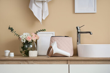 Wall Mural - Modern photoepilator with cosmetic bag and flowers on table near sink in bathroom