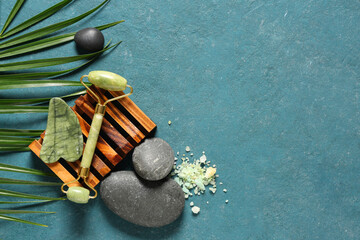 Wall Mural - Composition with facial massage tools, sea salt, spa stones and palm leaf on color background