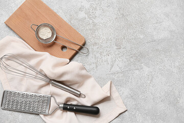 Canvas Print - Metal sieve with flour, wooden board, grater, whisk and napkin on grunge background