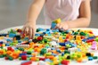 © New Africa - Girl playing with building blocks at white table indoors, closeup