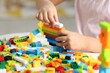 © New Africa - Girl playing with building blocks at white table indoors, closeup