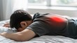 © han - Close-up of a person lying on a bed with a glowing red area on their back, symbolizing chronic pain and discomfort. Minimalistic composition with copy space, representing health issues and