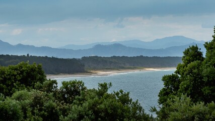 Poster - Scenic coastline with distant mountains.