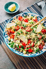 A bowl of fresh tabbouleh salad with chopped tomatoes, cucumbers, and parsley