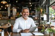 © MyJuly - man in a white shirt with a notebook or laptop is sitting in a restaurant. Business staff is smiling, success