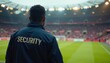 © 2April - Security guard with jacket looking at sports field, stadium seating in blurred background