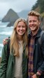 © natakot - A happy young couple stands together on a coastal path, with a stunning ocean view behind them. Their warm smiles and casual attire reflect a carefree day spent enjoying nature and each others company