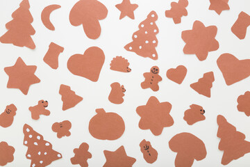 Wall Mural - Pattern of brown different gingerbread cookie shapes from application paper on light gray table background. Making and creating Christmas decoration elements. Closeup. Top down view.