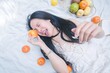 © AK ST - Young Woman Enjoying Fresh Citrus Fruits on Soft White Bedding