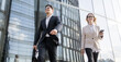 © muse studio - Business professionals in modern attire walk confidently on urban street during daytime
