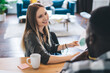 © BullRun - Woman sitting at table and talking to ethnic colleague