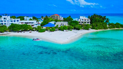 Wall Mural - Aerial top view of a beautiful island, waves, coral reefs in the ocean, luxury resort, and tropical paradise in the Maldives. Top-down drone view of the Indian Ocean.