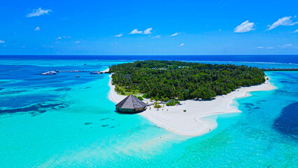 Wall Mural - Aerial top view of a beautiful island, waves, coral reefs in the ocean, and tropical paradise in the Maldives. Ttop-down drone view of the Indian Ocean.