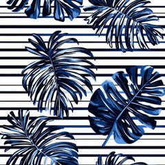 Wall Mural - Navy blue tropical leaves on a striped background, forming a seamless pattern.