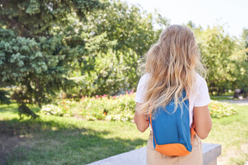 young caucasian female with backpack facing scenic park landscape on a sunny day.