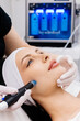 © wedmoments.stock - In a cosmetology clinic, a professional female cosmetologist performs a hydrafacial treatment on an attractive woman. Concept of beauty, skincare, and rejuvenation with advanced facial procedures.