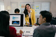 © PaeGAG - Young businesswoman leading a meeting with her team, discussing charts and statistics on a computer screen and printed documents in a modern office setting