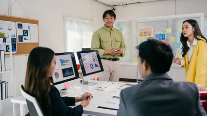 Fototapete - Asian businesspeople are discussing a project together during a business meeting, analyzing graphs and charts displayed on a computer and a whiteboard with sticky notes