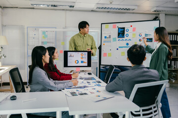 Wall Mural - Group of young asian businesspeople discussing charts and graphs on an interactive whiteboard during a presentation meeting focused on company growth and financial analysis