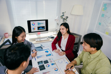 Fototapete - Four asian entrepreneurs are discussing company performance, analyzing charts and graphs, working together on business project in modern office using computer, documents, and financial reports