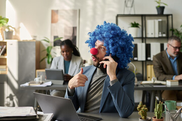 Poster - Young man in formalwear and clown wig discussing working points on mobile phone while sitting by his workplace